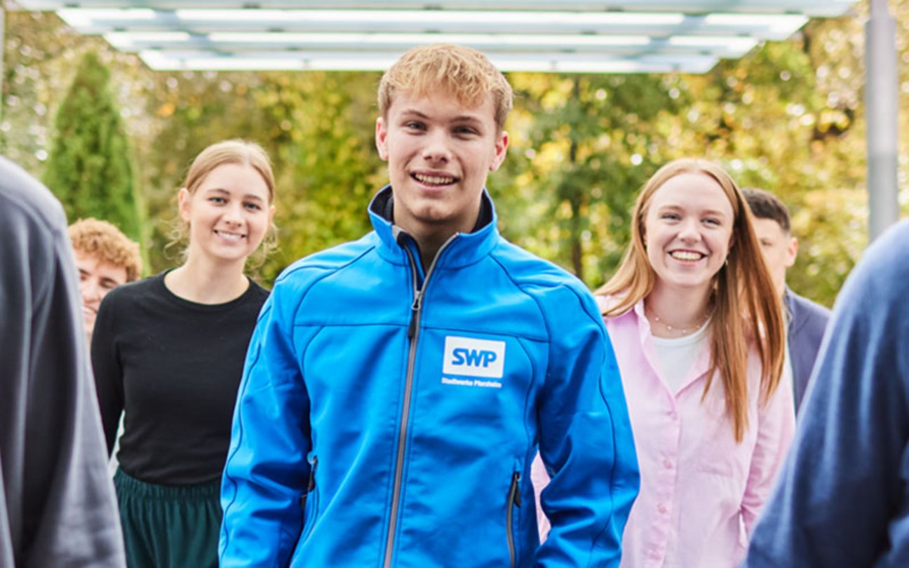 Das Bild zeigt drei junge Menschen, die in die Kamera lächeln.