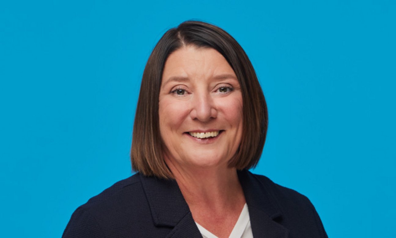 Bereichsleiterin für das Finanz- und Rechnungswesen Inken Barth lächelt in die Kamera vor blauem Hintergrund.