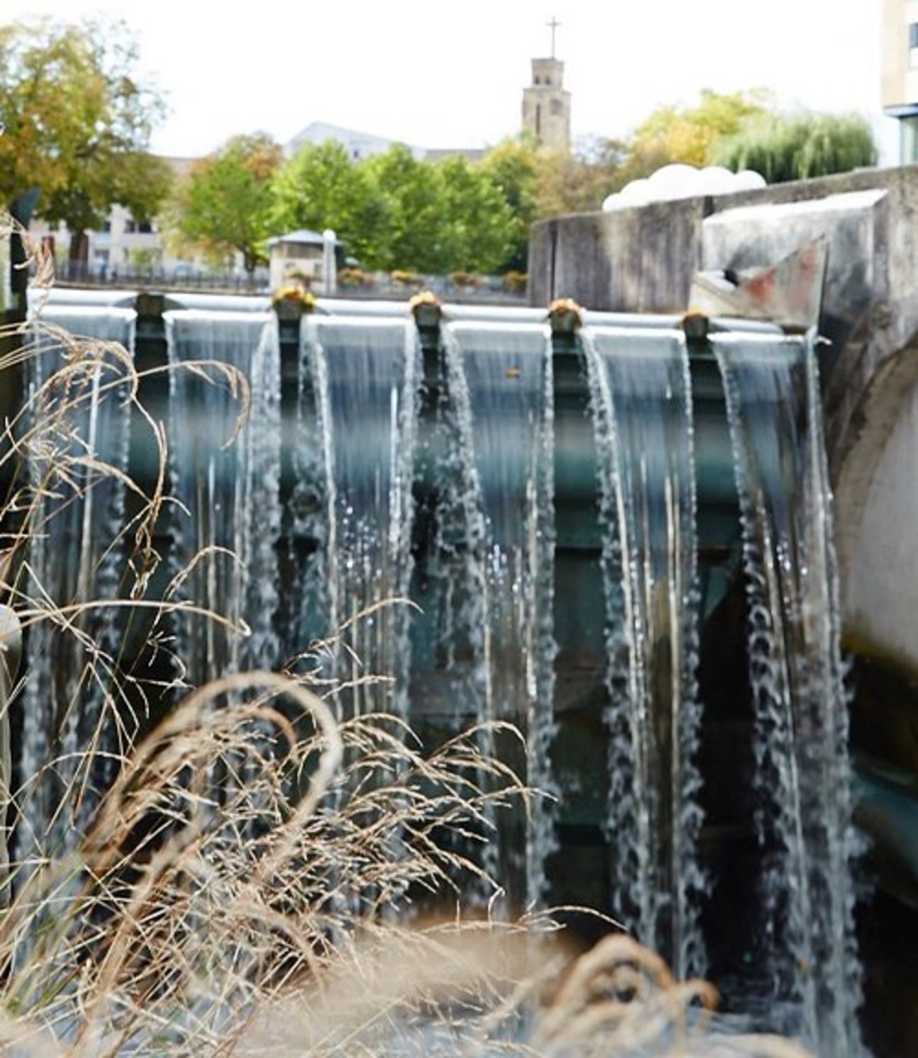 Wasser strömt in mehreren Bahnen über eine moderne Wasserkraftschnecke mit angrenzender Betonmauer