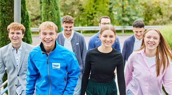 Junge Frau sitzt an einem Schreibtisch und arbeitet an einem Desktop-Computer in modernem, hellem Raum.