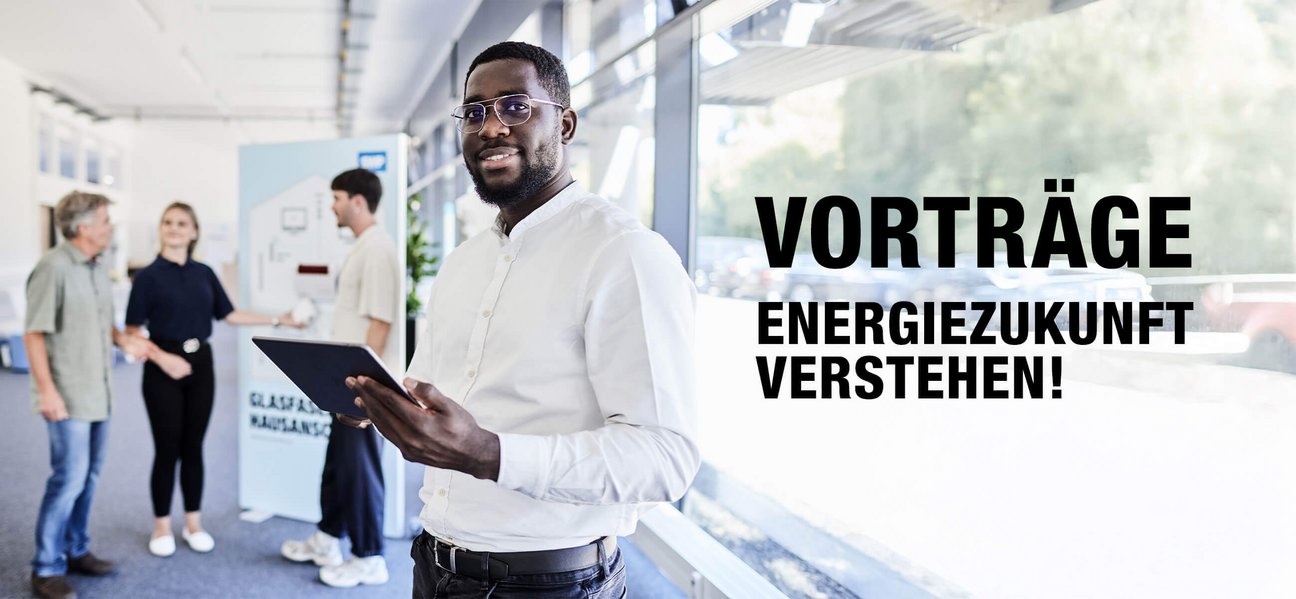 ann mit Tablet steht in hellem Foyer, im Hintergrund Gesprächssituation; Text im Bild: „Vorträge – Energiezukunft verstehen!“